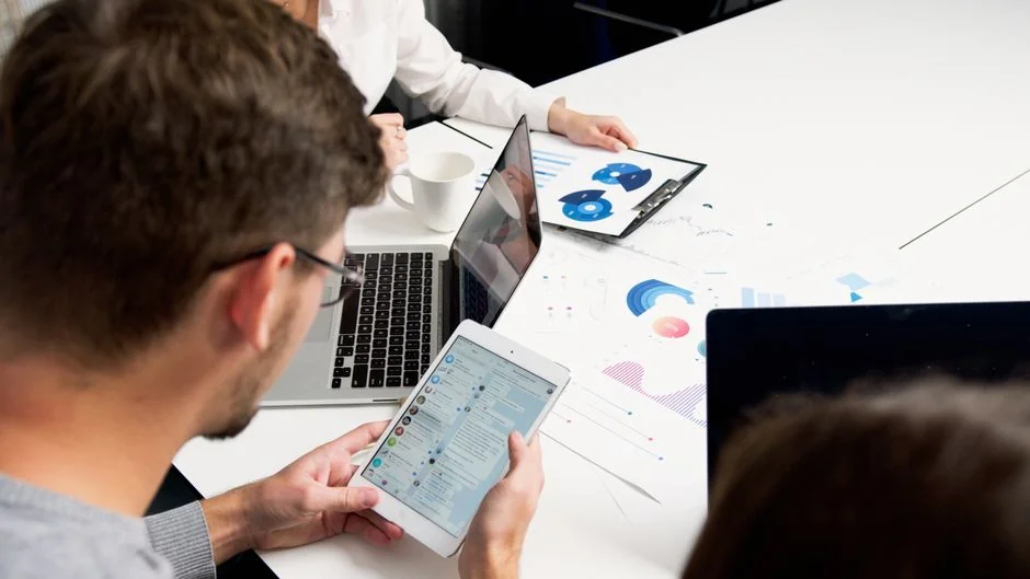 Professionnel en train d'évaluer des graphiques financiers sur un ordinateur portable dans un bureau contemporain.
